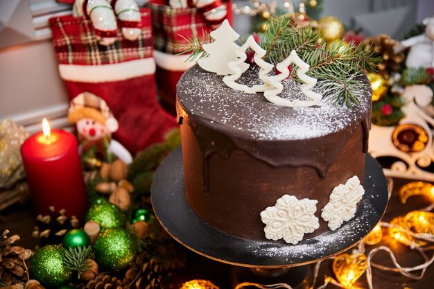 Christmas cake made of chocolate base with chocolate cream decorated with Christmas trees