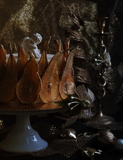 christmas cake with golden pear decor on dark shiny background.