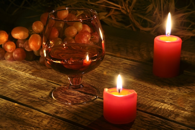 Christmas candles, grapes and glass with cognac or whisky 