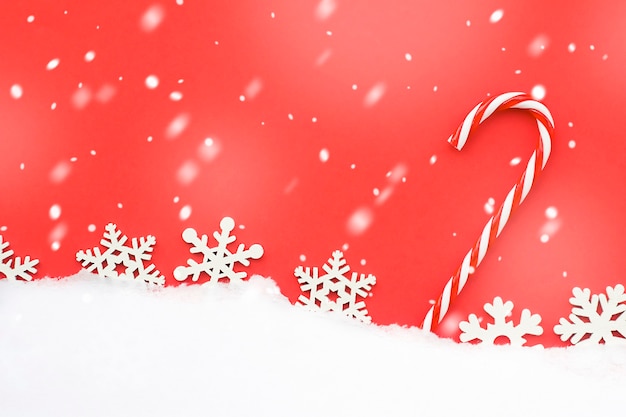 Foto bastoncino di zucchero di natale e fiocchi di neve su sfondo rosso