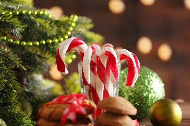 Bastoncini di zucchero di natale in vetro con decorazioni natalizie sul tavolo su parete luminosa