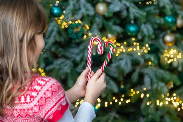 Christmas candy canes in the hands of a child. Selective focus. Holiday.