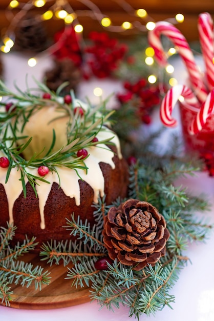 Christmas caramel cake, decorated with white chocolate, cranberry, rosemary and New Year decorations. Festive baked goods. Soft selective focus. Vertical