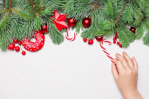 Christmas card background border composition with candy sweets and kid hand. Flat lay, top view with copy space