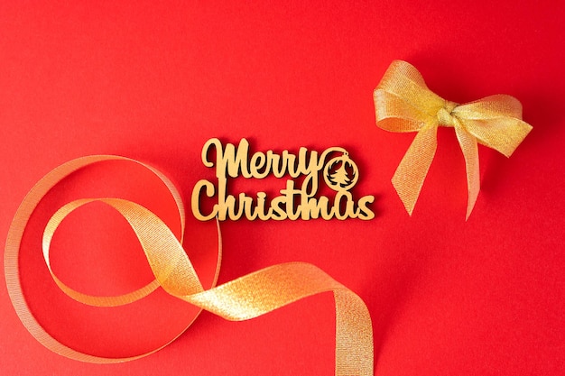 Christmas card lettering Merry Christmas on a bright red background with ash ribbon and bow