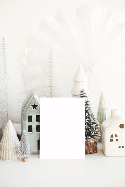 Photo christmas card and little scandinavian village empty greeting card and christmas trees and houses decorations on white table postcard template with space for text happy holidays