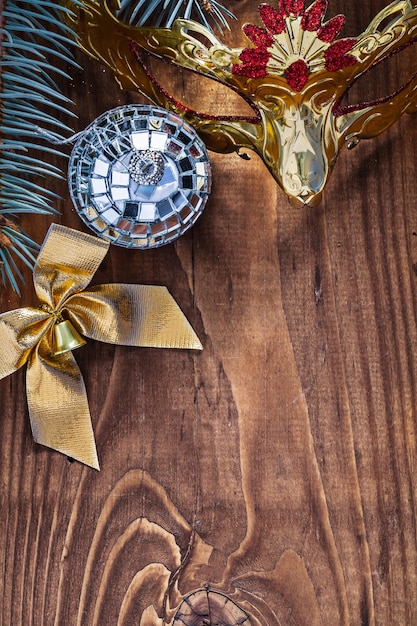 Christmas card mirror disco ball gold colored bow carnaval mask and pine tree branch on old wooden board with copyspace