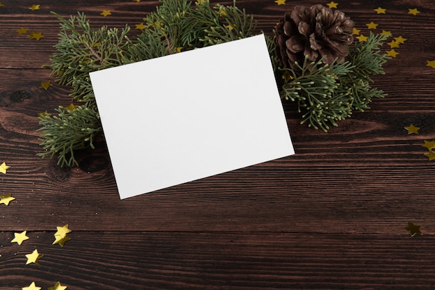 Christmas card mockup template with fir twigs and golden stars on a vintage wooden.