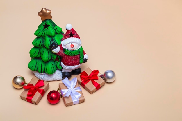 Biglietto natalizio. albero di capodanno con un pupazzo di neve e regali su fondo beige. primo piano con copia spazio