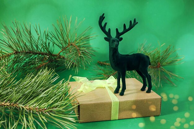 Christmas card toy deer on a wrapped gift pine branches on a green background bokeh side view space for text