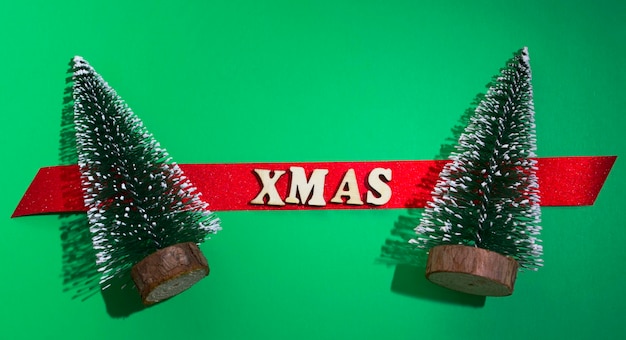 Christmas card. Two Christmas trees with greetings. Red spruce with the words xmas. green background