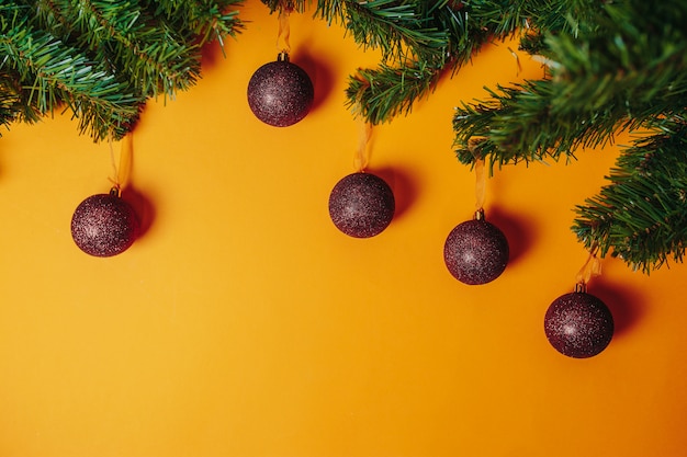 Christmas card with copyspace. Christmas ornaments flat lay on the orange . Red balls and fir branches around.