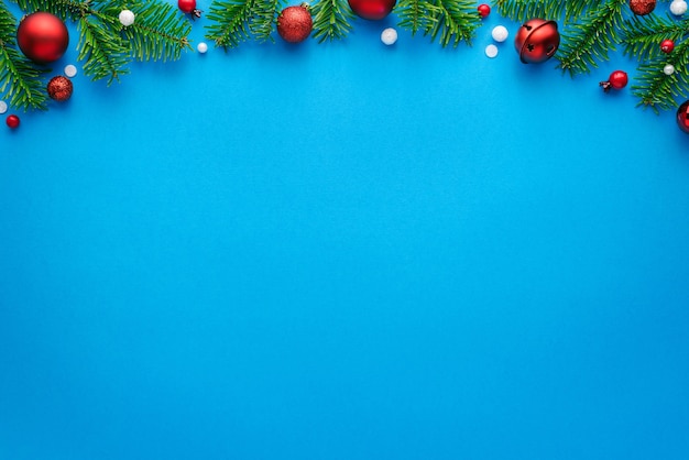 Christmas card with fir decorations on a blue background. Top view with copy space for festive text