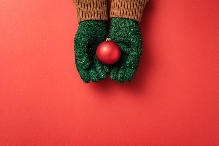 Photo christmas card with a red glass ball in the hands of a girl