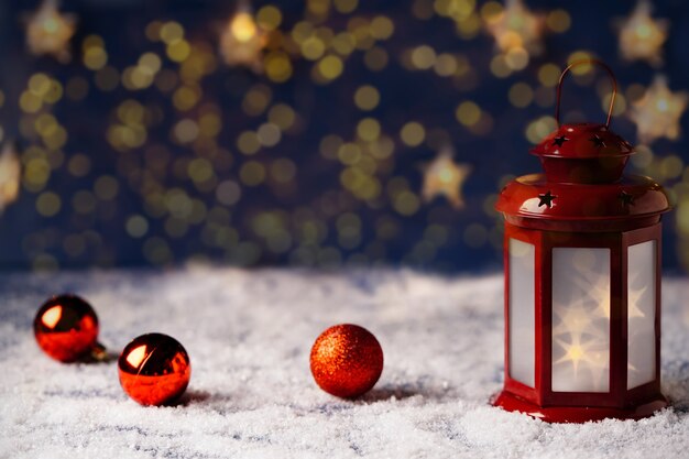 Foto cartolina di natale con una lanterna rossa con stelle su uno sfondo di bokeh dorato