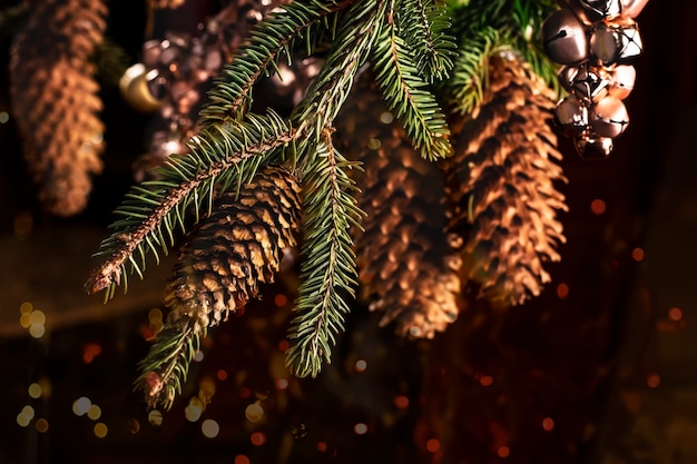 Christmas card with a spruce branch with big cones toys from pink bells for Christmas and New Year