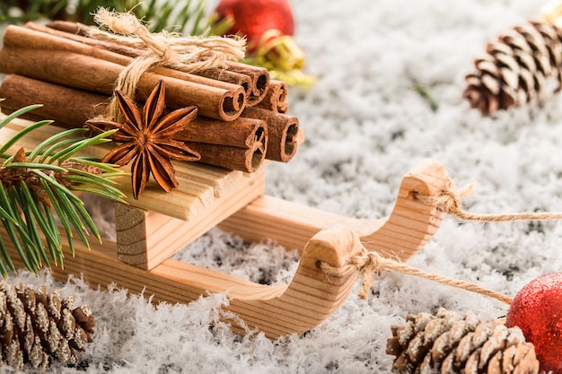     Christmas card with wooden sled with heap of cinnamon