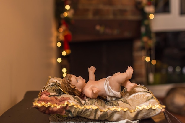 Christmas cards Baby Jesus vintage figurine in his crib with christmas lights and fireplace in background