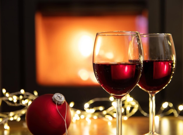 Christmas celebration Red wine glasses and decoration on table fireplace background Xmas celebration