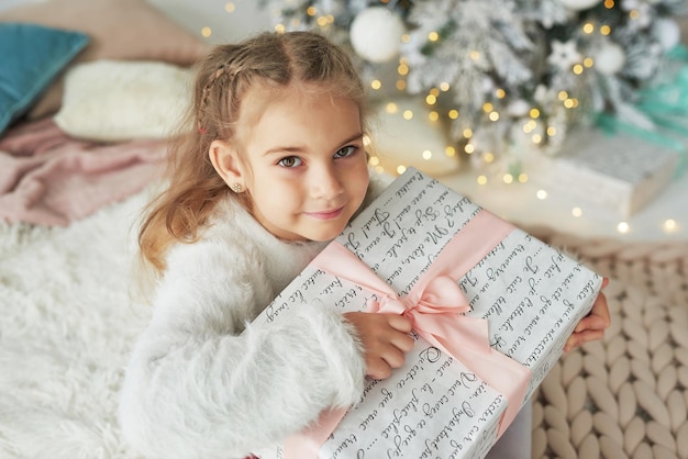 Рождественский ребенок на фоне елки с подарком.