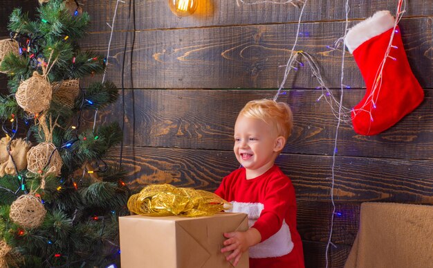 Natale bambini carino bambino vicino all'albero natale bambini sorridente bambino che fa capolino da dietro cri...