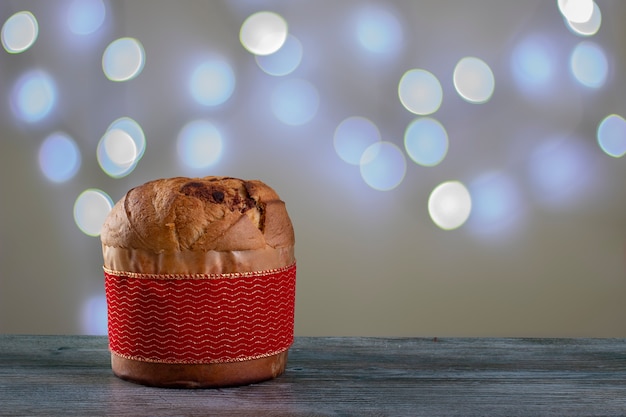 Foto panettone di torta al cioccolato di natale con una striscia rossa in uno sfondo chiaro o panettone chocotone