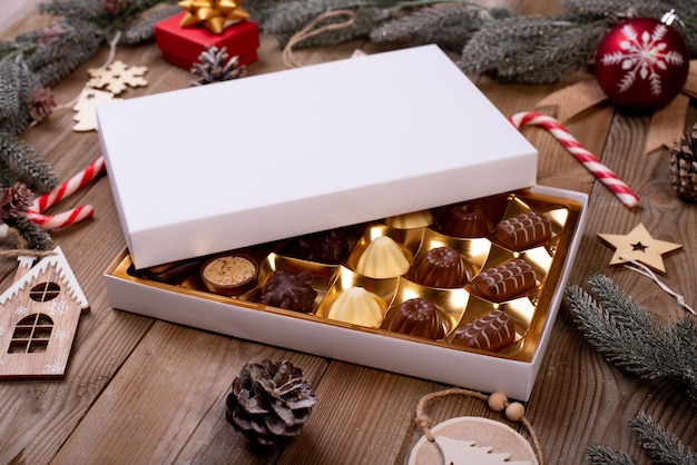 Foto scatola di caramelle al cioccolato di natale su un tavolo di legno con decorazioni per le vacanze stagionali