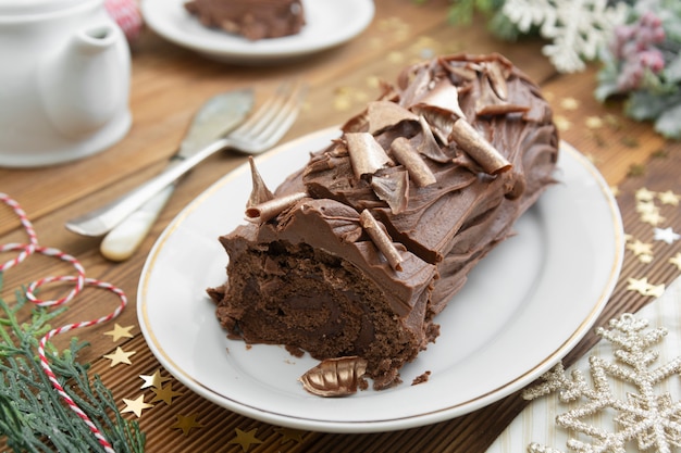 Christmas chocolate swiss roll isolated on a wooden table. Chocolate sweet dessert. Pastry for breakfast or tea.