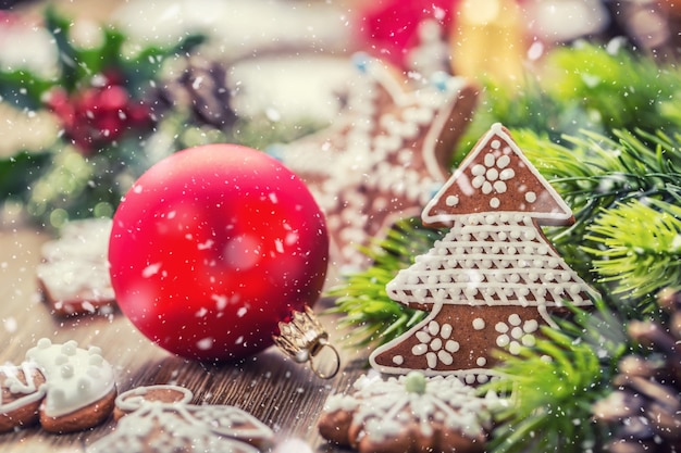 Рождество. Елочный шар, печенье, пряники, сосновая шишка и украшение в снежной атмосфере.