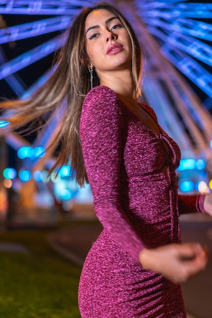 Christmas in the city at night decoration in winter Portrait of a young brunette woman smiling on an illuminated Ferris wheel