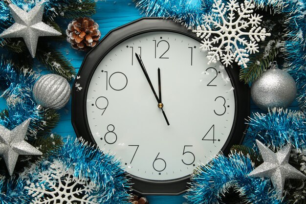 Christmas clock with winter decoration on snow. Happy new year concept.