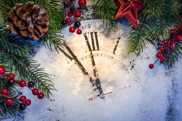 Christmas clock with winter decoration on snow