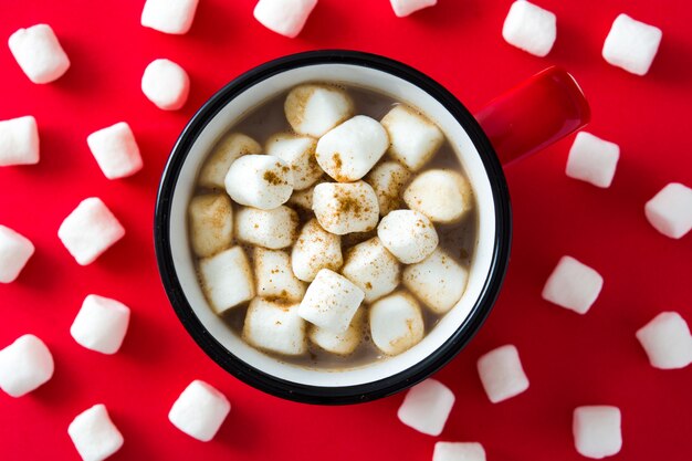 Christmas cocoa with marshmallow in mug on red. Top view