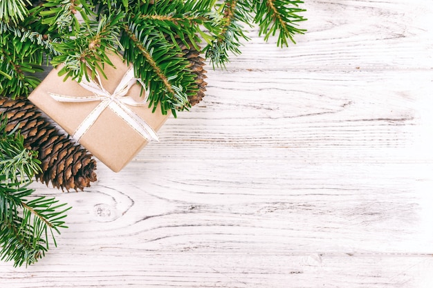 Christmas composition background. Christmas gift with pine cones and fir branches on wooden background. Flat lay, top view, copy space. Toned.