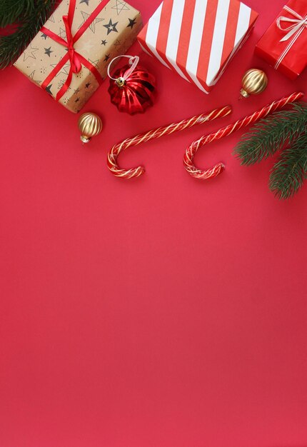 Christmas composition. boxes as gift on branch fir tree on red backgraund. Top view, copy space