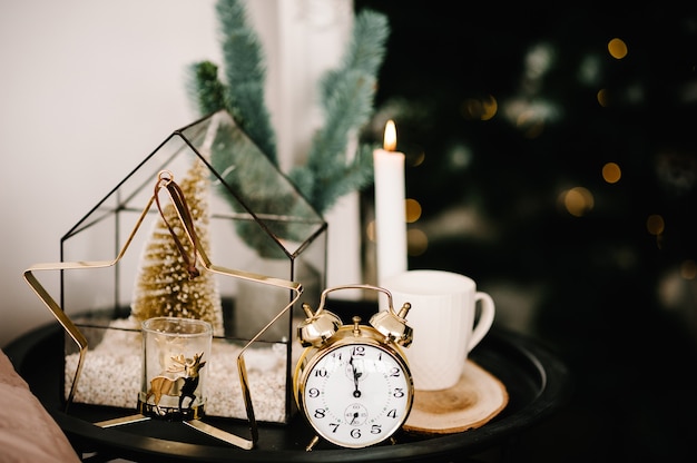 Christmas composition. Candle, cup coffee, vintage gold clock, metal gold candle holder in the shape of a star on the table. Interior and decoration at home. Close up. Christmas holiday eve.