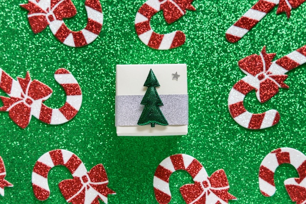 Foto composizione di natale. natale candy cane pattern e confezione regalo su sfondo verde lucido. buone vacanze e concetto di nuovo anno.