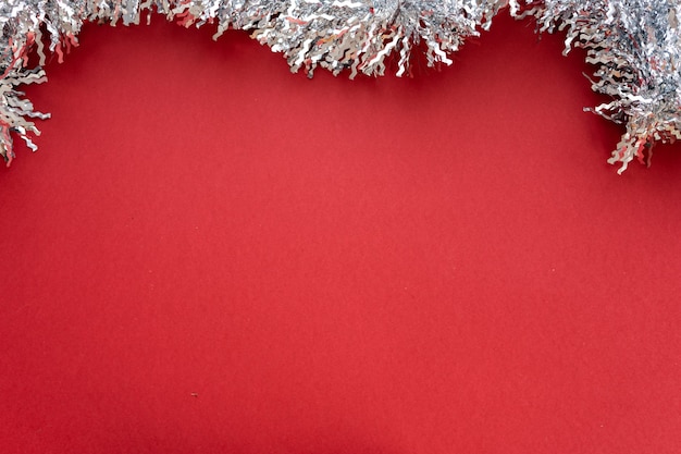 Christmas composition. Christmas decoration white tinsel on a red background. Flat lay, top view, space for text