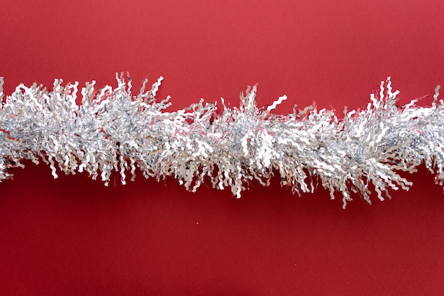 Christmas composition. Christmas decoration white tinsel on a red background. Flat lay, top view, space for text