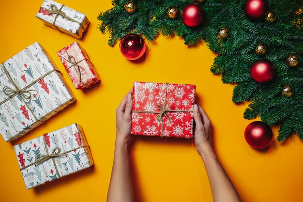 크리스마스 구성. 크리스마스 선물, 전나무 가지. 평평한 누워, 평면도, 복사 공간. 빨간 크리스마스 공. 여자는 크리스마스 선물을 보유하고있다.