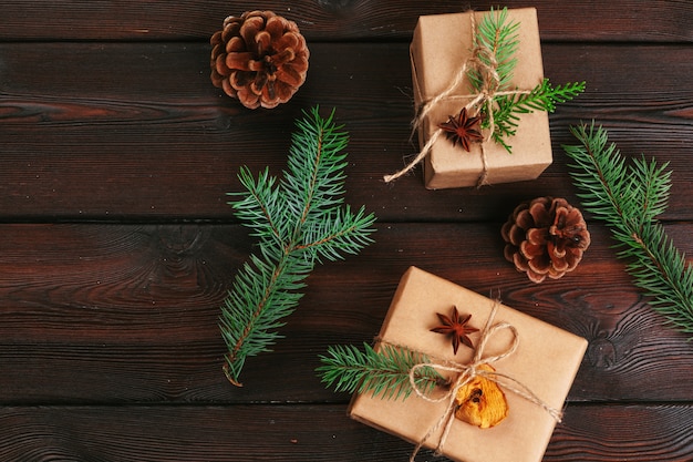 Composizione di natale regalo di natale, coperta a maglia, pigne, rami di abete su legno