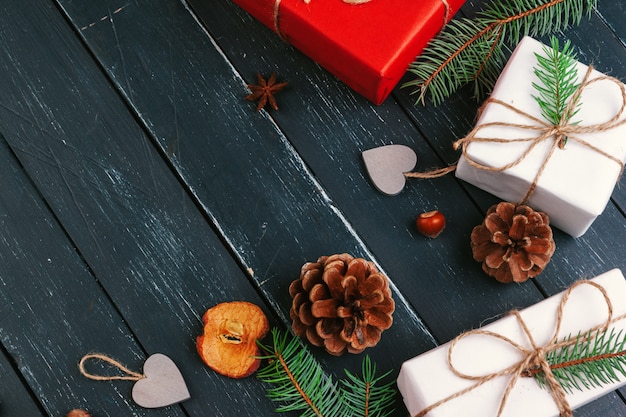 Christmas composition. Christmas gift, knitted blanket, pine cones, fir branches on wooden background.