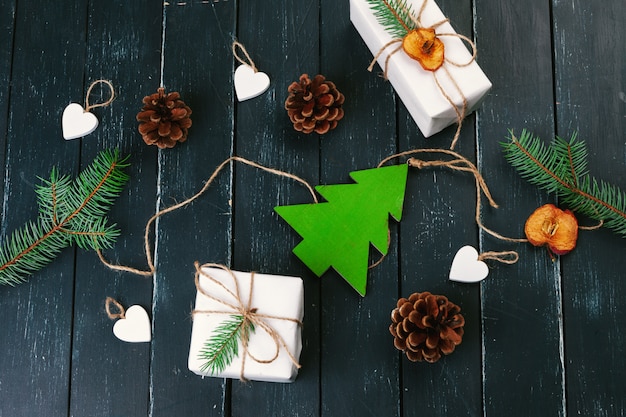 クリスマスの組成クリスマスプレゼント、ニット毛布、マツ円錐形、木製の背景にモミの枝。