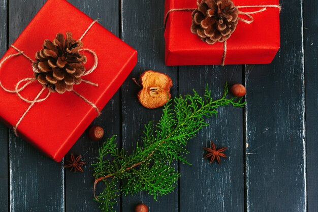 Christmas composition. Christmas gift, knitted blanket, pine cones, fir branches on wooden background.