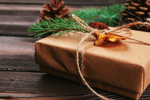 Christmas composition. Christmas gift, knitted blanket, pine cones, fir branches on wooden background.