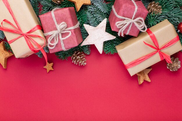 Christmas composition. Christmas red decorations, fir tree branches with toys gift boxes on red wall. Flat lay, top view, copy space