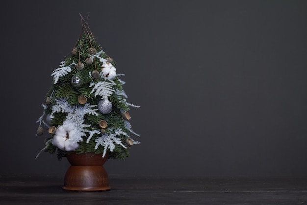 Natale e composizione. albero di natale fatto di rami di abete e decorato con materiali naturali e palline in un vaso di terracotta