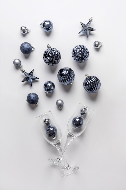 Christmas composition of classic blue balls and glasses of champagne on grey.