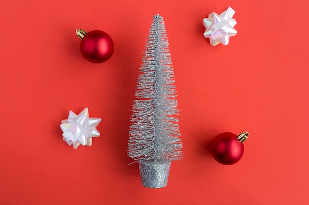 Christmas composition. Creative silver christmas tree and red balls on the red  background. Top view. Copy space.