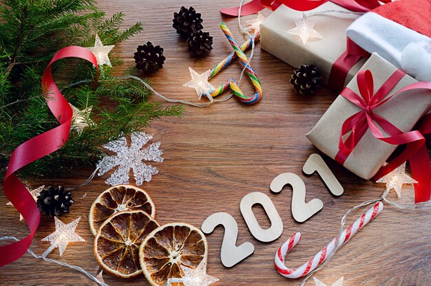 Christmas composition on a dark wooden background with a spruce branch, gifts, sweets and a garland